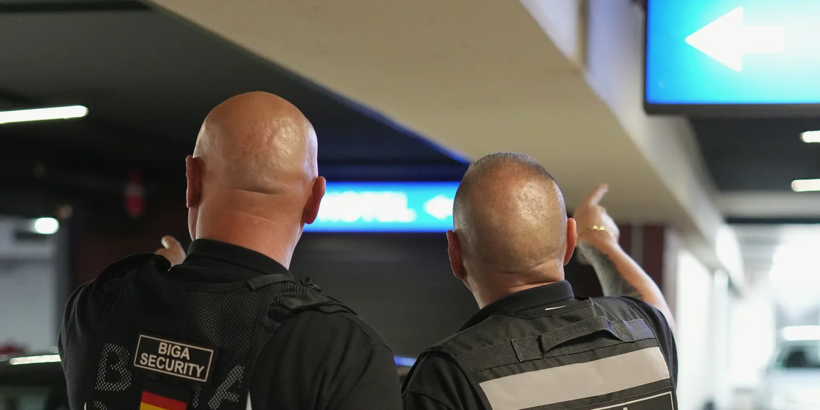 Zwei Mitarbeiter von BIGA Security auf Streife in einem Parkhaus, einer weist auf die Beschilderung
